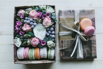 Colorful handmade macaroons in a gift box with flowers