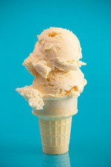 A Double Scoop Vanilla Ice Cream Cone on a Blue Background