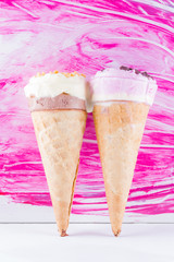 Melted ice cream with chocolate and nuts on a pink background. Two ice cream cones in pop art style. Summer milk dessert in a waffle cone. Summer concept