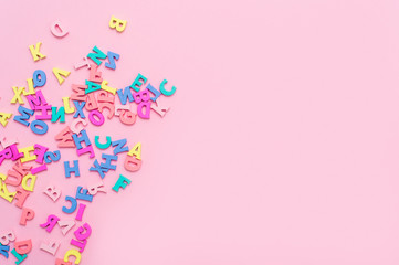 Many multicolored wooden letters on a pink background. toy letters. english alphabet. View from...