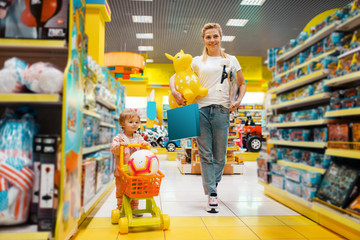 Mother with girl buying a lot of toys in store