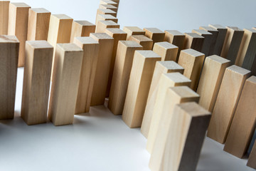 Many curved lines of wooden cubes are connected in the center into one, as a symbol of queues, a variety of tasks and a leader, on an uneven white background. Horizontal frame