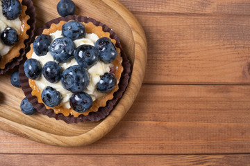 bilberry tartlet on a wooden plate on the table, bilberry baked shell, fruit cupcake with blueberry
