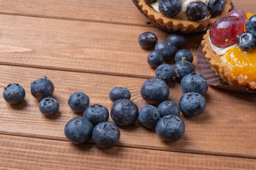 bilberry tartlet on a wooden plate on the table, bilberry baked shell, fruit cupcake with blueberry