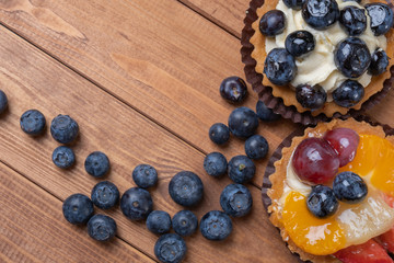 fruit tartlets on a wooden plate on the table, fruit baked shell, fruit cupcake with berry