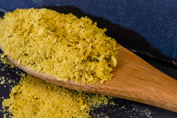 Close-up of Nutritional (Brewer's) Yeast Flakes on wooden spoon. High level of detail and rich texture.