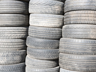 Used, old tires stacked one on another next to shop garage.