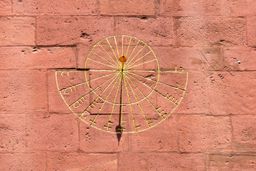 Golden sundial on sandstone facade