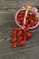Strawberries in a small basket on the wooden table. Place for your logo or text