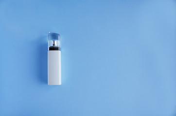  White bottle of perfume on a blue background. soft focus. copy space.