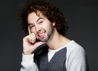  Handsome young man touching his head and smiling while standing against grey background