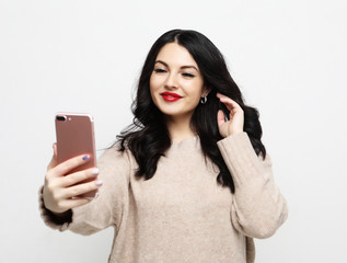 Fototapeta premium Fashion curvy brunette girl taking photo makes self portrait on smartphone