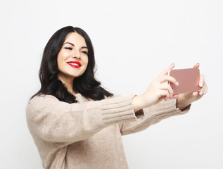 Fashion curvy brunette girl taking photo makes self portrait on smartphone
