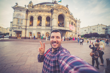 happy tourist take selfie in front of the national opera and ballet theatre building, Kyiv, Ukraine.