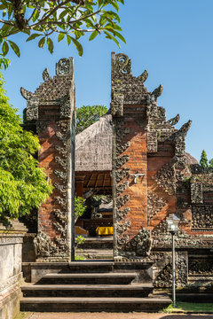Ubud, Bali, Indonesia - February 26, 2019: Batuan Temple. Smaller Split gate separates two mandalas, courtyards under blye sky and with green foliage.