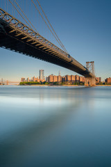 Fototapeta na wymiar Williamsburg bridge and Lower East Side Manhattan from East River during golden hour with long exposure photo