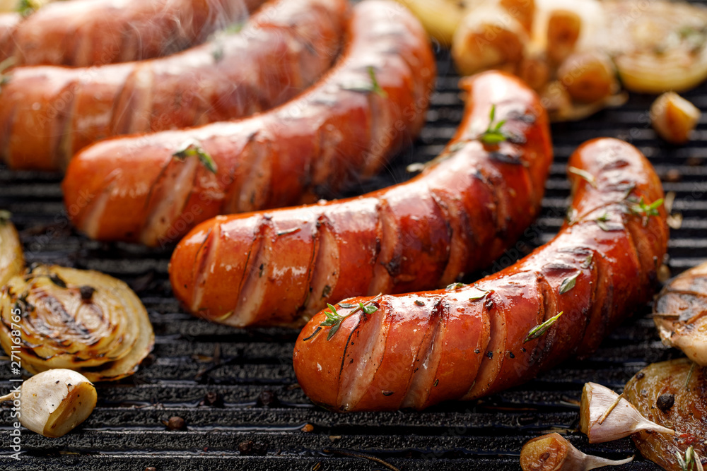 Wall mural grilling sausages with the addition of herbs and vegetables on the grill plate, close-up. grilling f