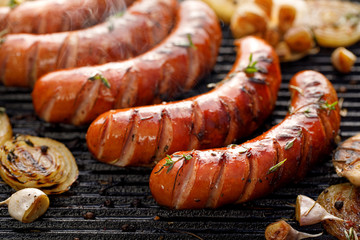 Grilling sausages with the addition of herbs and vegetables on the grill plate, close-up. Grilling...