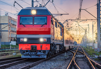 Fototapeta na wymiar Passenger train departs from the station at sunset time.