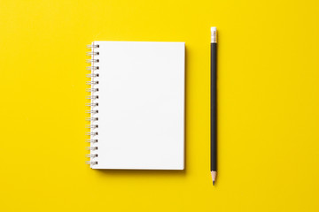 Blank notebook with pencil on yellow background.minimal style.Top view. 