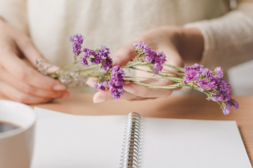 Obraz na płótnie Canvas Woman hand holding purple dry flower on desk office.