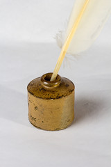 An old Feather quill in antique inkwell on a white background