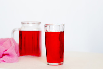 Fototapeta na wymiar Fruit and berry red juice in glasses and jug on a white background. Fresh and cold summer drink.