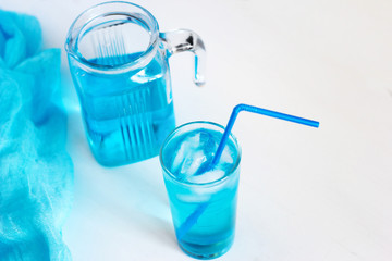 Glass with a blue cocktail with ice on a white background.