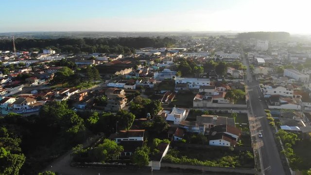 Drone flying over a low-income urban area in Cruz das Almas, Bahia, Brazil. Show houses, small buildings in the neighborhood, and green environnement. Drone slowly moving down.