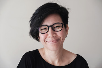 Portrait of happy and healthy natural looking middle aged Asian woman wearing glasses and smiling at camera, women's day, stop Asian hate concept  - Powered by Adobe