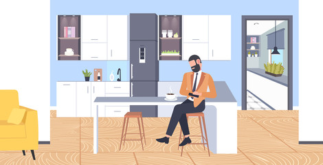 businessman sitting at counter man using smartphone mobile app communication concept modern coffee point kitchen interior flat full length horizontal