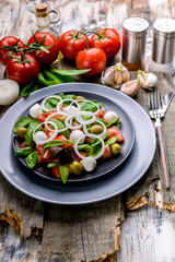 Healthy and tasty salad from fresh herbs with mozzarella, tomatoes, olives and onions. Mediterranean traditional cuisine. Vertical shot