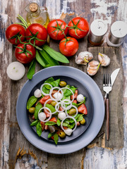 Healthy and tasty salad from fresh herbs with mozzarella, tomatoes, olives and onions. Mediterranean traditional cuisine. Top view. Flat lay