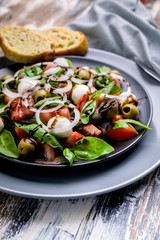 Close up Delicious Mediterranean salad made from fresh herbs with mozzarella, tomatoes, olives, onions and balsamic dressing. Italian traditional cuisine.