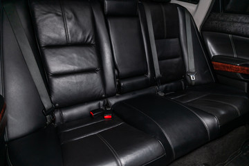Сlose-up of the car   interior: black leather rear seats and seat belts .