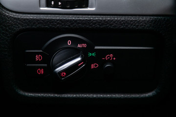 Сlose-up of the car  black interior:  dashboard,headlight adjustment buttons and other.