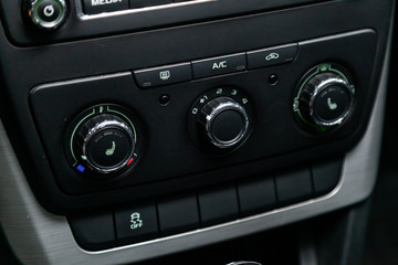Сlose-up of the car  black interior:  seat heatting buttons, adjustment of the blower, air conditioner and other buttons.