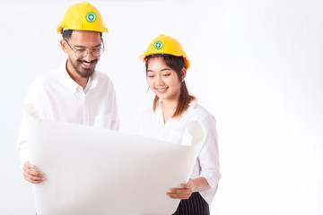 Young engineer and architect holding and working together on building site blueprint at construction site or factory. Engineering and architecture concept.