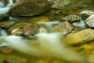 Naklejka premium water in the stream rushing down the rocky creek inside park 