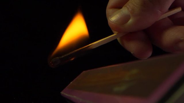 Slow motion of a match that burns at fingertips, blows out on it.