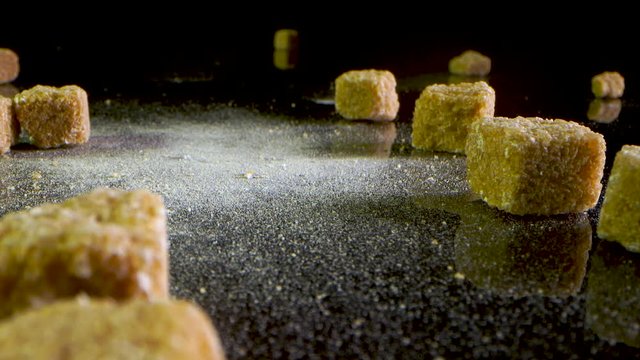Pieces of brown sugar falling on a black mirrored table at normal speed. Laowa lens.