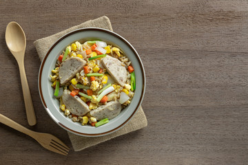 top view of fried rice with vietnamese pork sausage and vegetable in a ceramic dish on wooden table. asian homemade style food concept.