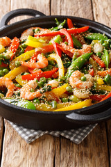 Delicious Asian stir fry of shrimp with vegetables, sesame close-up in a frying pan. vertical
