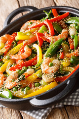 Stir-Fried shrimp with vegetables, sesame close-up in a pan on the table. vertical