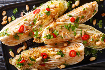 Delicious appetizer fried napa cabbage with soy sauce and peanuts closeup on a plate. horizontal top view