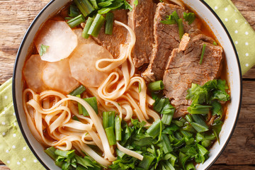 Asian soup made of stewed or braised beef, broth, vegetables and Chinese noodles closeup in a bowl....