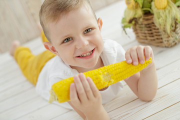 Boy child with corn at home 