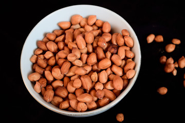 Peanut seeds on a plate with a blank black background