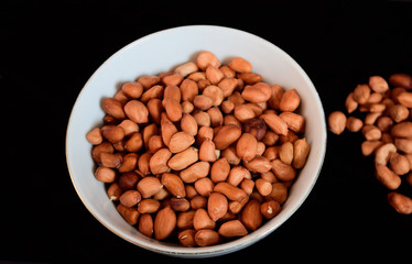 Peanut seeds on a plate with a blank black background