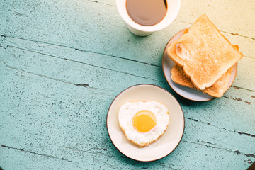 Fried eggs, toast, coffee, breakfast set placed on a blue wooden table